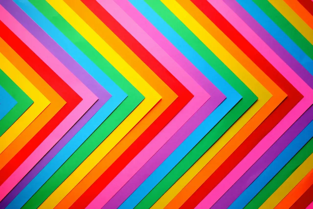 Tęczowe paski papieru układają się w kształt strzałek, symbolizując różnorodność i to, co oznacza skrót LGBT.