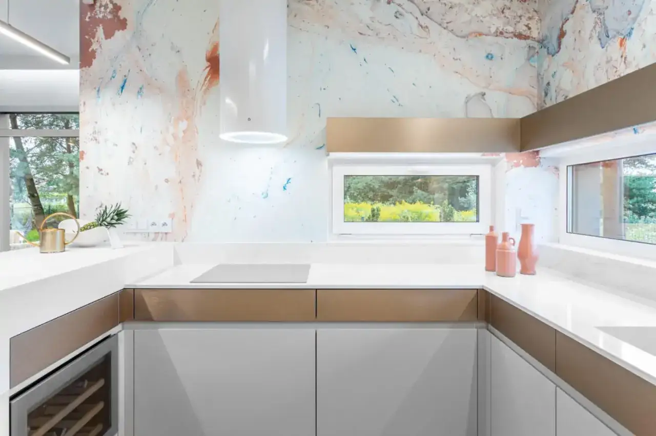 Nowoczesna kuchnia z białym blatem kuchennym na ścianie zamiast płytek, ozdobionym abstrakcyjnym wzorem.