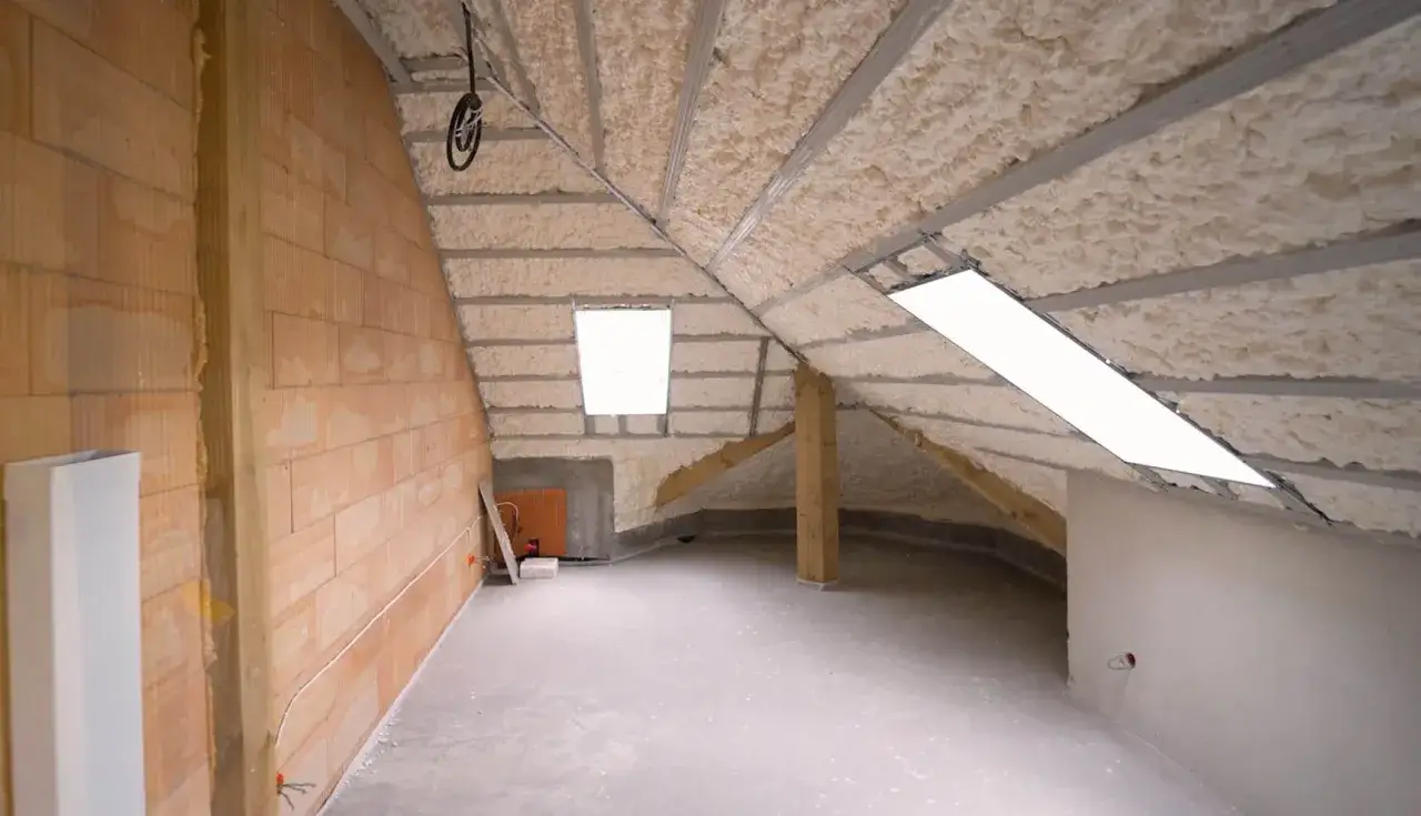 Poddasze w trakcie prac wykończeniowych, z widocznym ocieplaniem pianką PUR na skosach dachu.