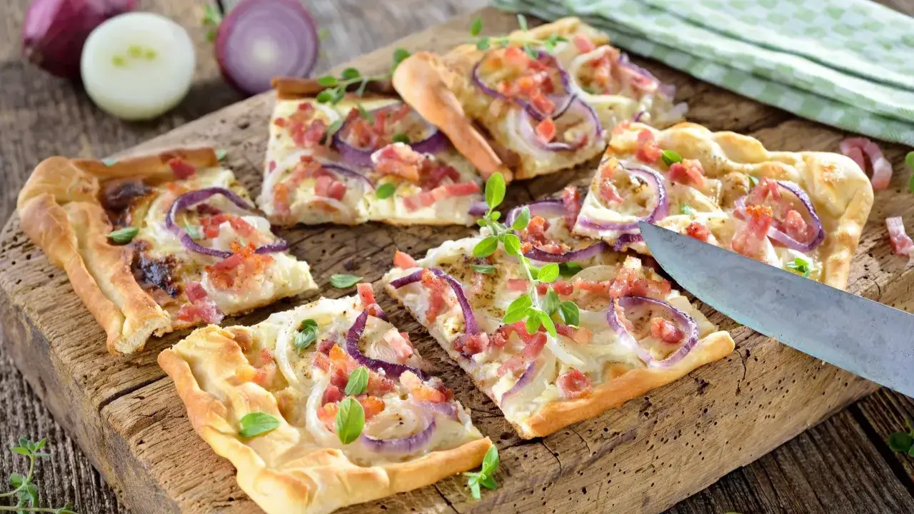 Pyszna pizza z gotowego ciasta z cebulą i boczkiem, pokrojona na desce. Idealna na szybki obiad, pokazująca jak zrobic pizze z gotowego ciasta.
