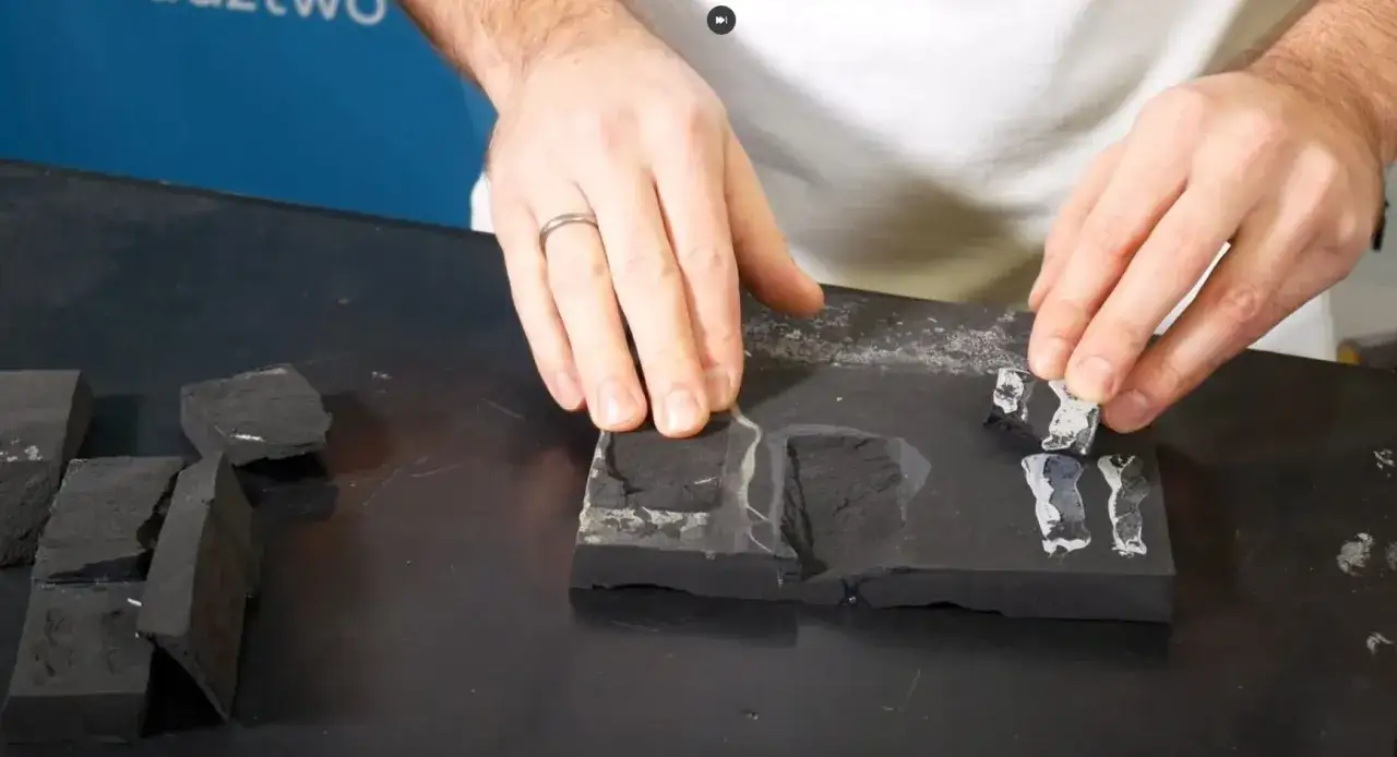 Dłoń układa fragmenty EPDM na styropianie, demonstrując klejenie.