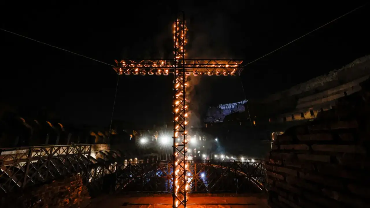 Płonący krzyż w nocy, symbolizujący Drogę Krzyżową. Otoczony starożytnymi murami, tworzy mistyczną atmosferę.