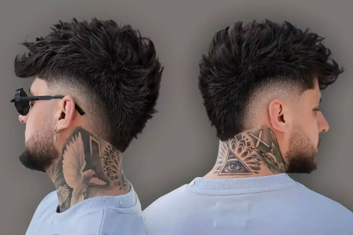 Mężczyzna z tatuażami na szyi prezentuje nowoczesną fryzurę mullet z wycieniowanymi bokami.