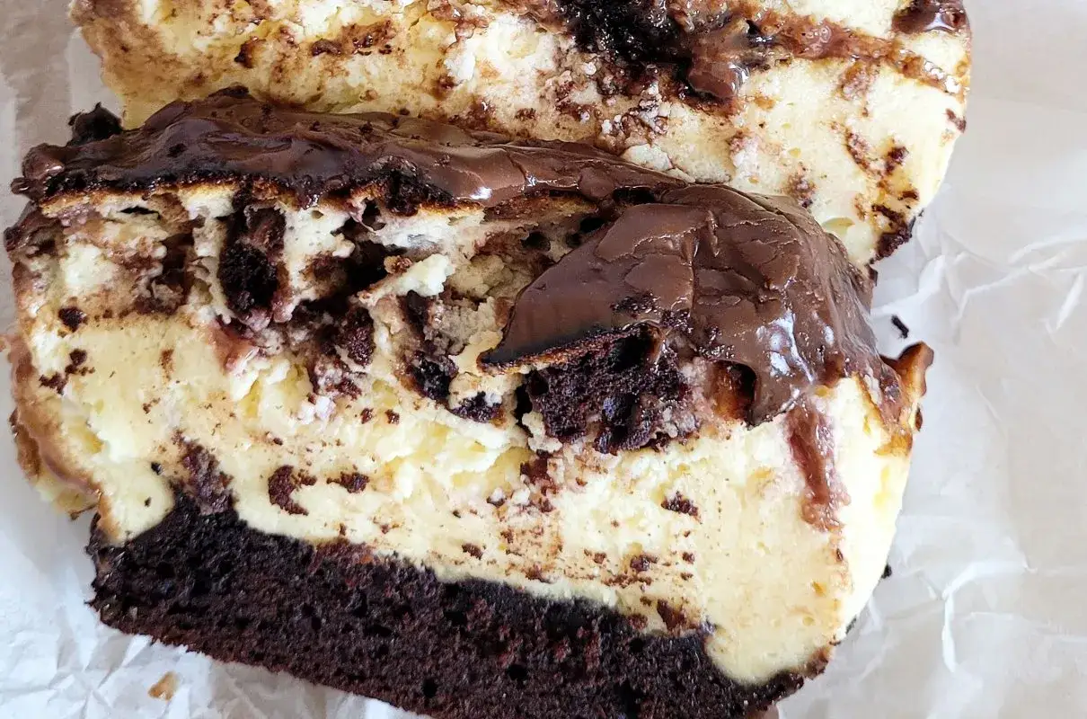 Pyszny murzynek z serem, z polewą czekoladową i kawałkami ciasta czekoladowego.