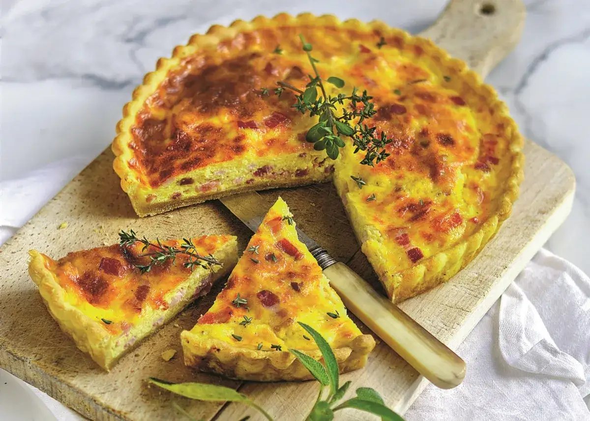 Pyszne tarty na słono z boczkiem i ziołami, pokrojone na desce, gotowe do podania.