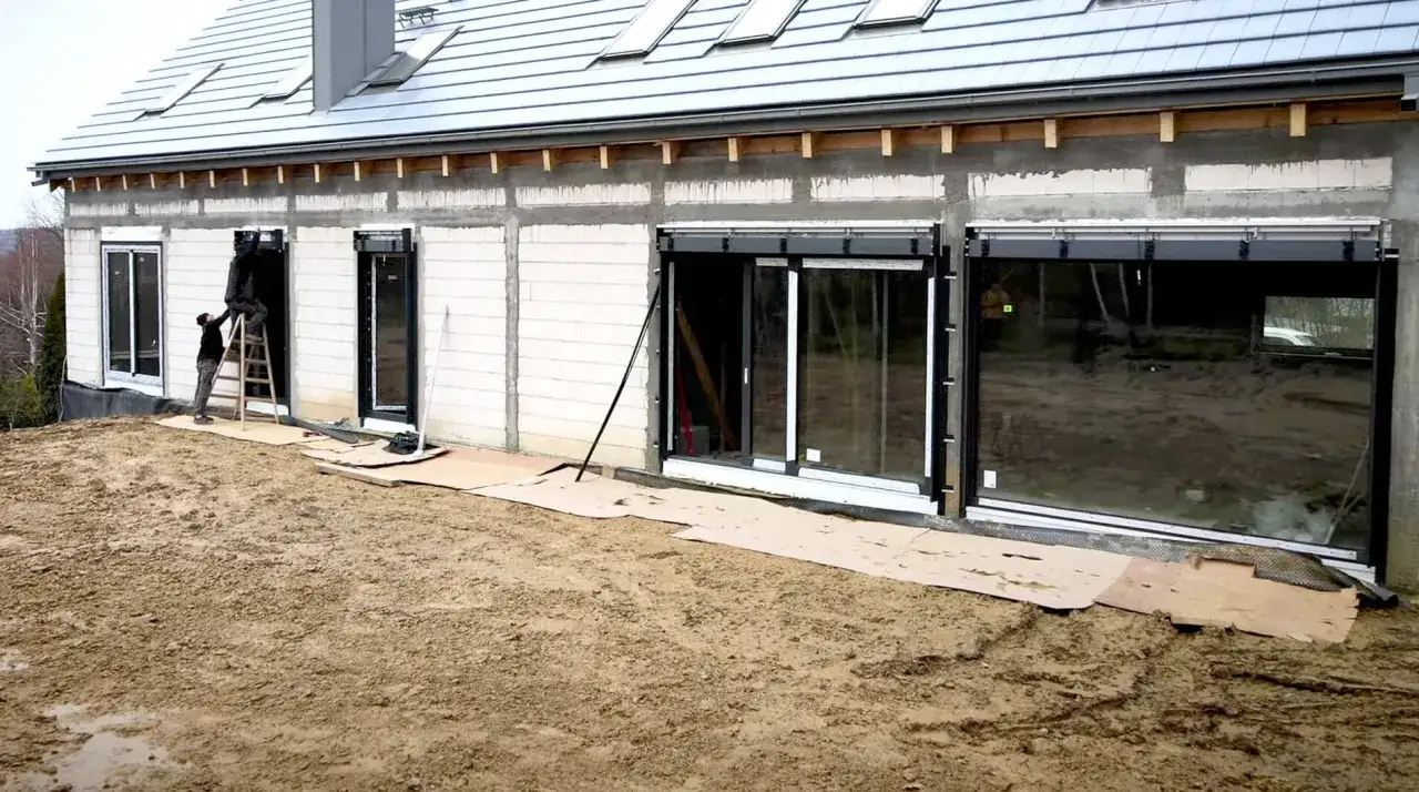 Pracownicy montują okna w nowym domu. Czy przy elewacji robocizna liczy się za okna?