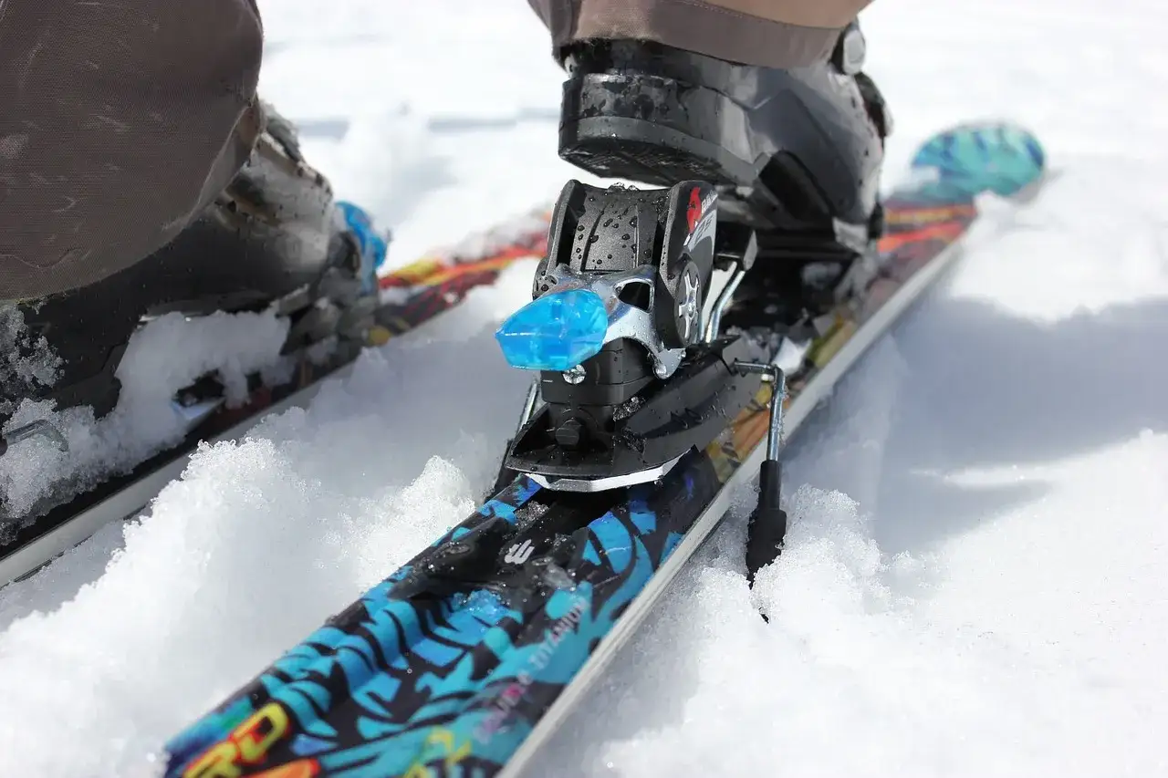 Narty z butami w śniegu. Czy snowboard jest bezpieczniejszy od nart? To pytanie zadaje sobie wielu narciarzy.