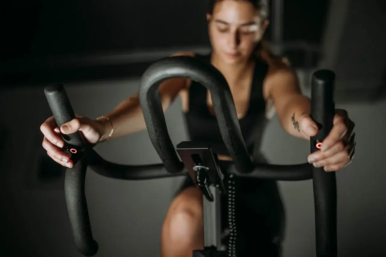 Kobieta ćwiczy na rowerku stacjonarnym, który pomaga w odchudzaniu brzucha.