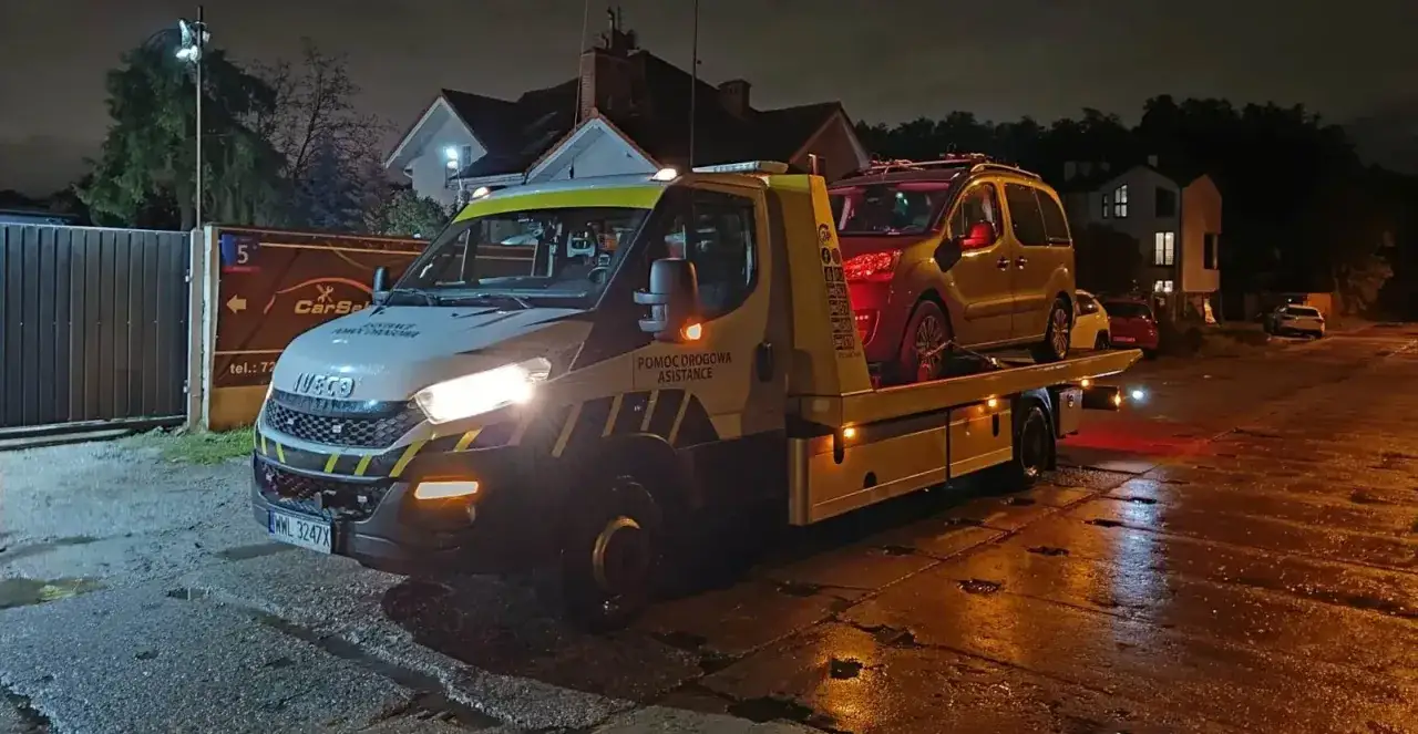 Pomoc drogowa assistance nocą. Auto na lawecie, gotowe do transportu.