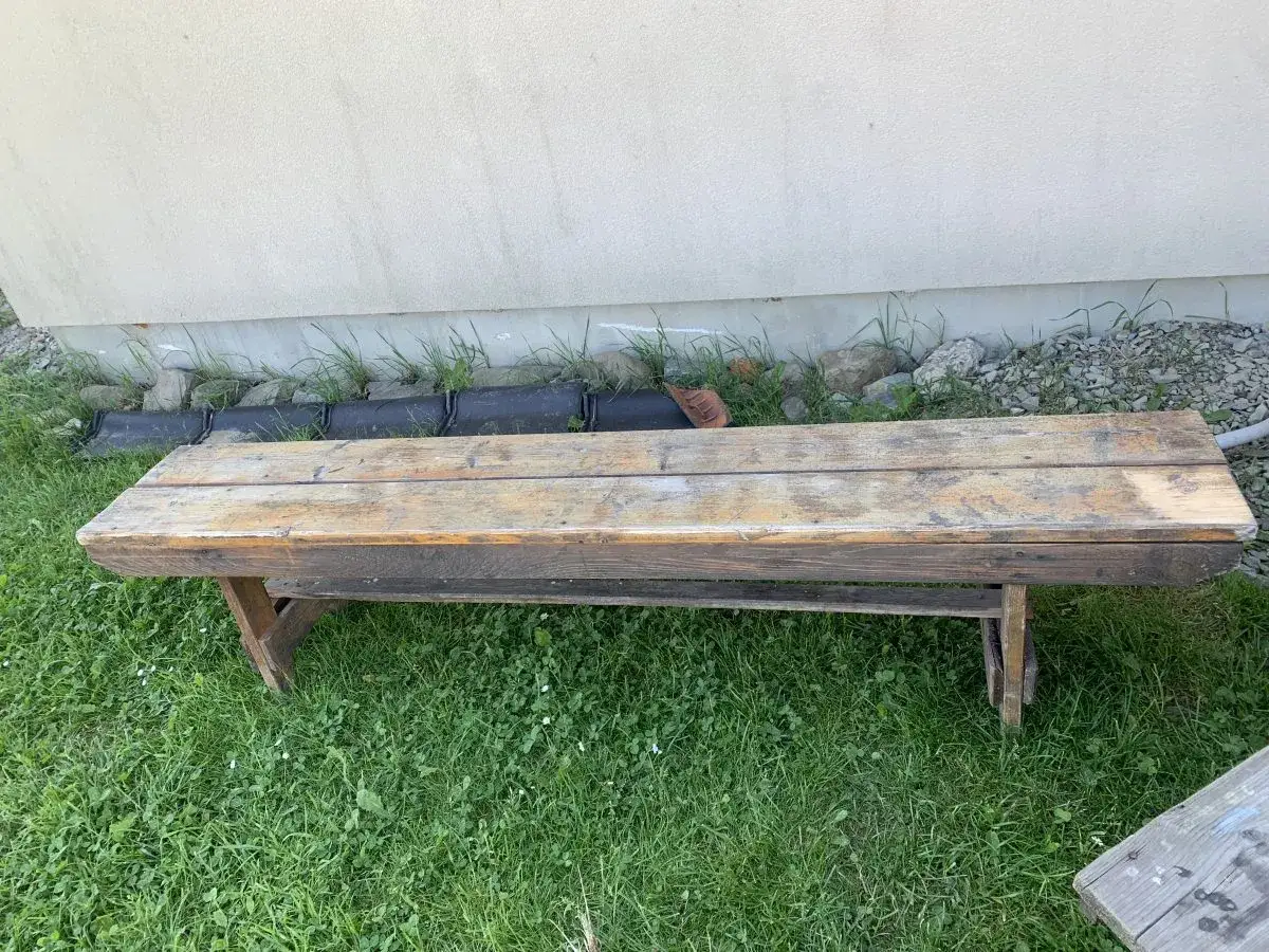 Drewniana ławka na trawie, z widocznymi śladami żywicy. Dowiedz się, jak pozbyć się żywicy z ławek, by odzyskać jej dawny blask.