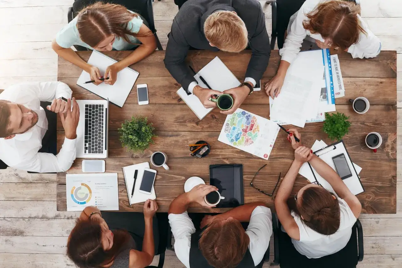 Ludzie przy stole, każdy z notatkami i kawą, tworzą inspirujące cytaty o ludziach, kt&oacute;rych spotykamy.