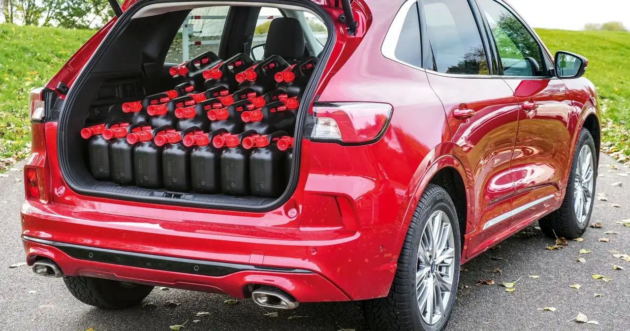 Czerwony SUV z pełnym bagażnikiem czarnych kanistrów z paliwem. Zastanawiasz się, ile paliwa można przewieźć przez granicę?