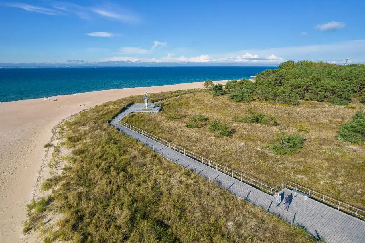 Spacerem po plaży na cyplu helskim, wzdłuż wydm i sosnowego lasu, podziwiając błękit morza.