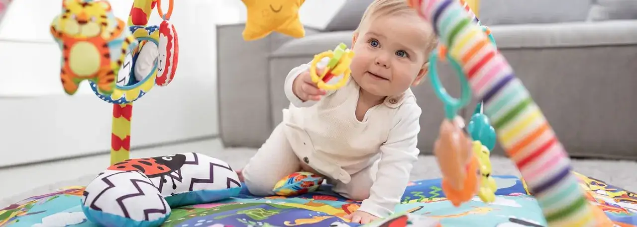 niemowlę na macie edukacyjnej z pałąkami