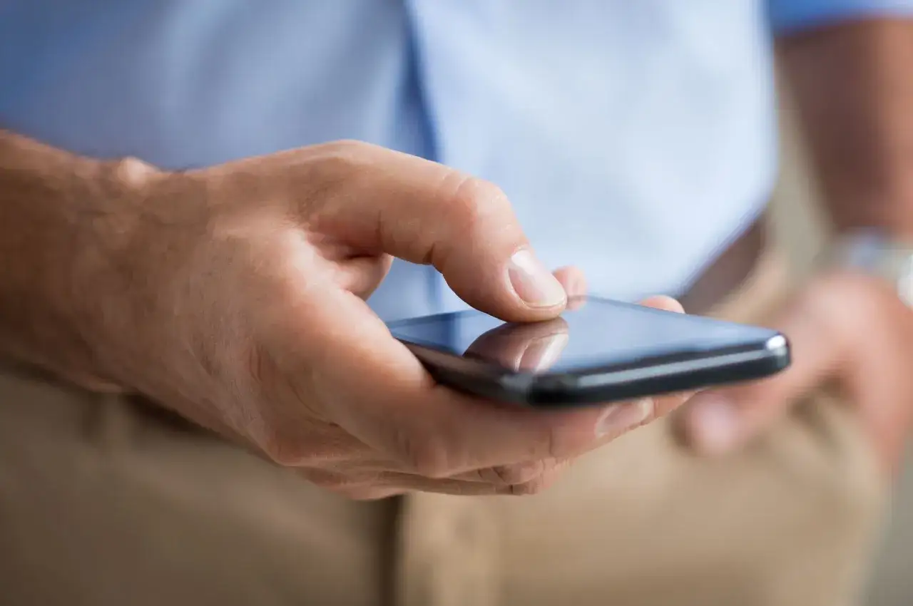 Dłoń trzyma smartfon, być może sprawdzając, co to roaming przed podróżą.