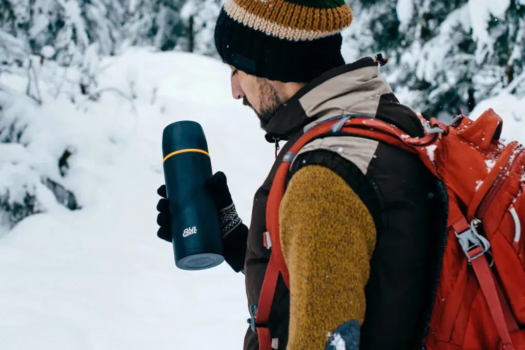 turysta z termosem w górach zimą