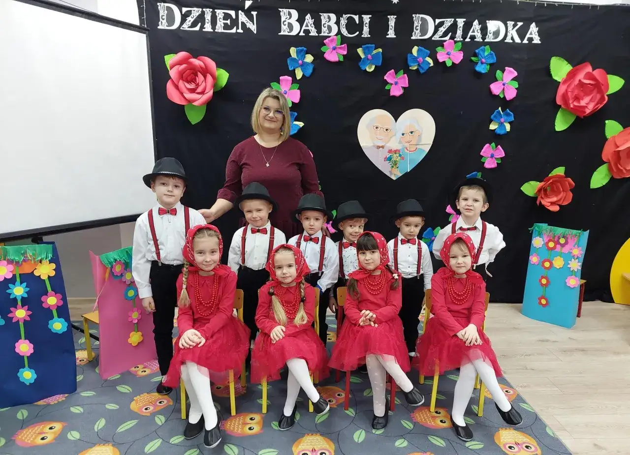 Dzieci w przedszkolu świętują Dzień Babci i Dziadka. Scenariusz uroczystości obejmuje występy maluch&oacute;w w strojach ludowych.