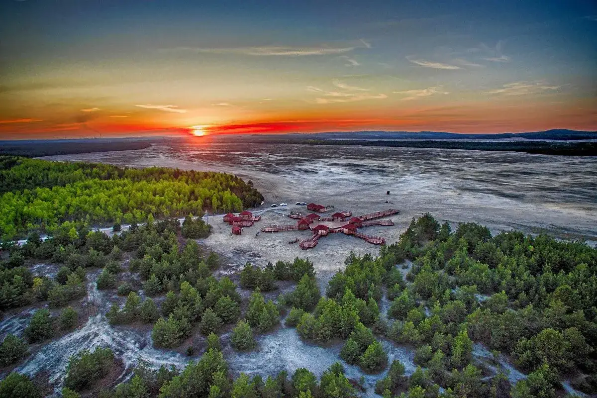 Zachód słońca nad Pustynią Błędowską, gdzie drewniana konstrukcja przypomina różę wiatrów.