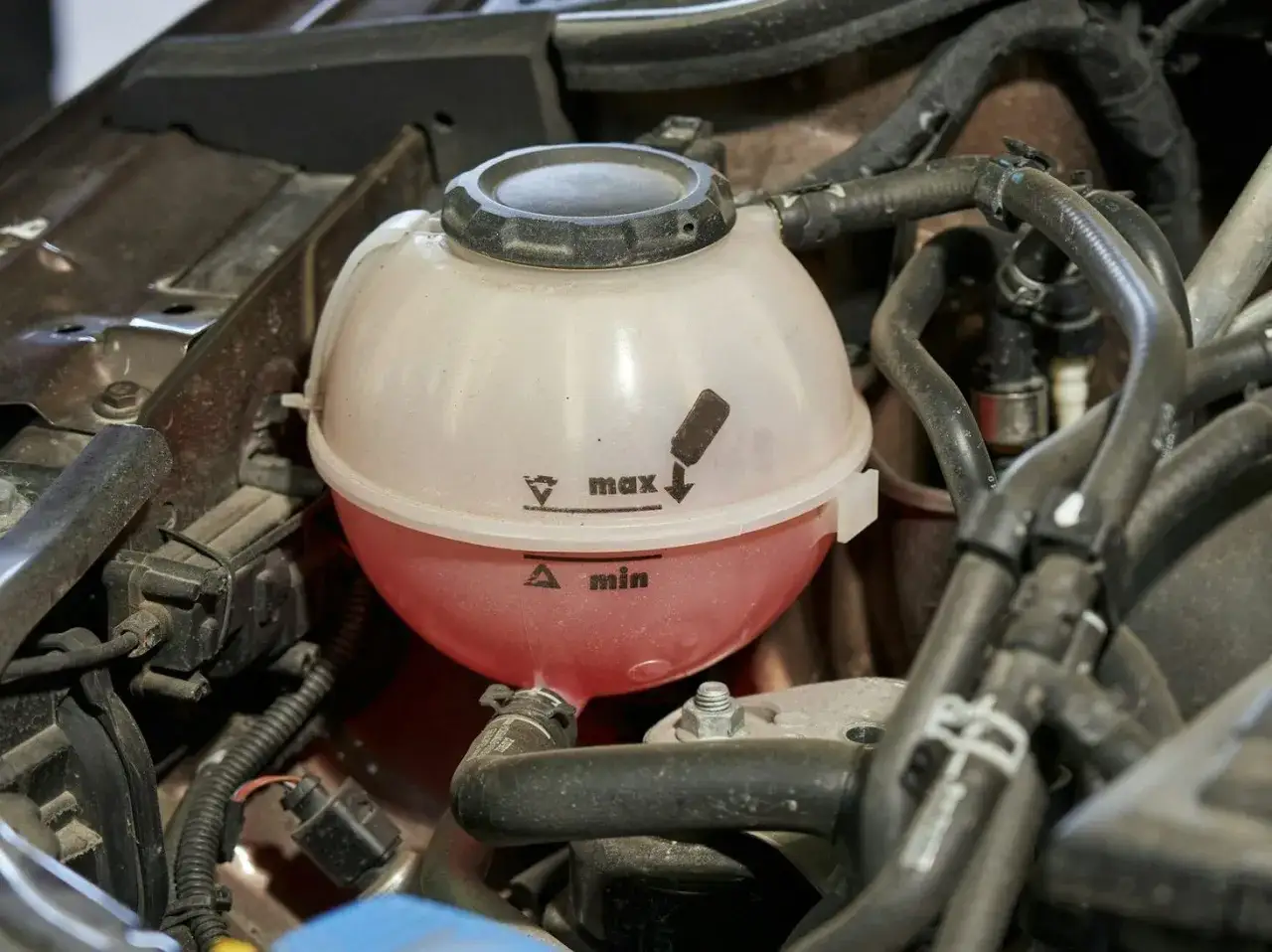 Zbiorniczek płynu chłodniczego z oznaczeniami max/min. Dowiedz się, jak wymienić płyn chłodniczy, sprawdzając jego poziom.