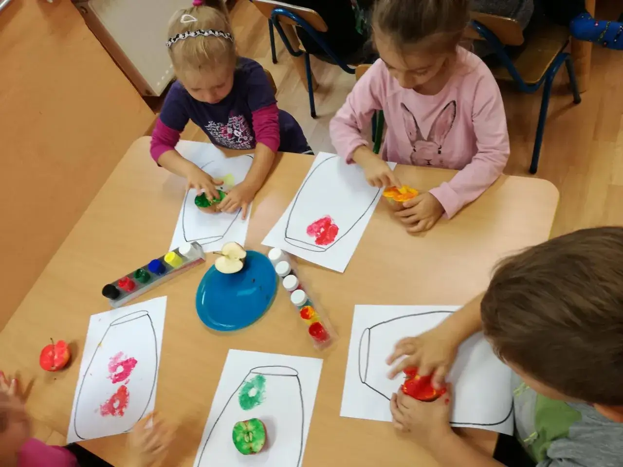 Dzieci tworzą pomysły na prace plastyczne owoce i warzywa, malując jabłkami na papierze.