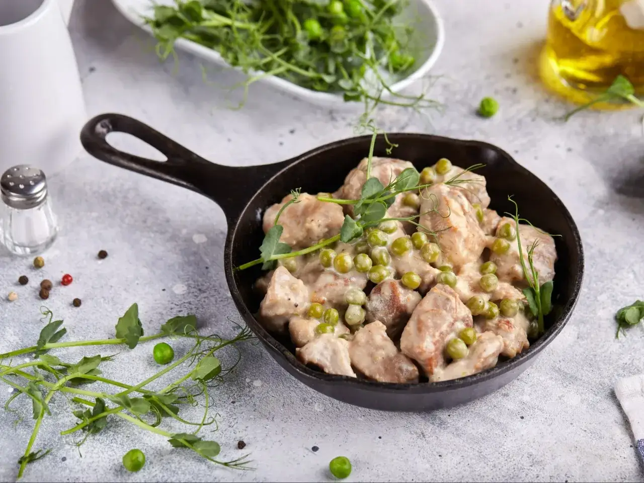 Duszone kawałki wieprzowiny z groszkiem w sosie, podane w żeliwnej patelni. Idealne danie, gdy zastanawiasz się, ile dusić wieprzowinę.