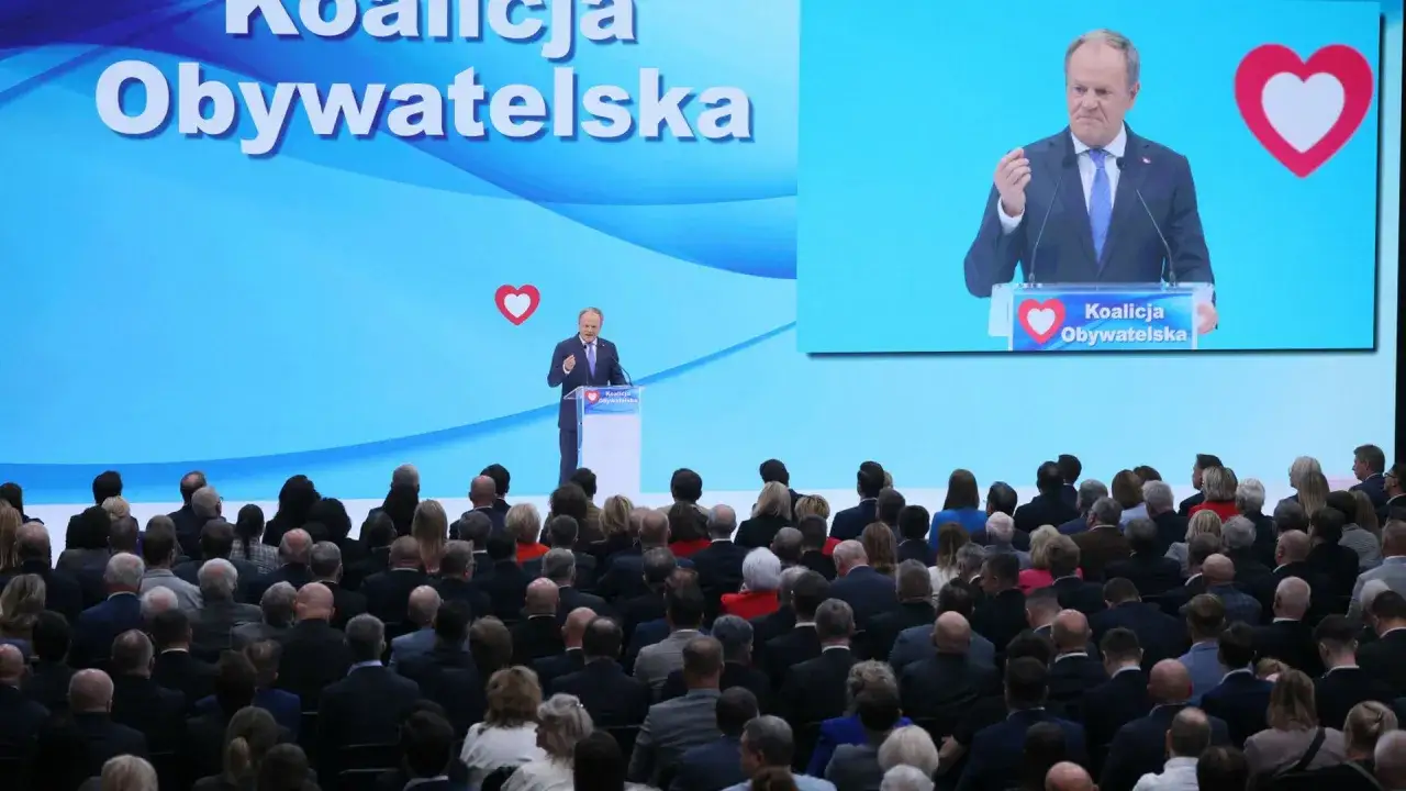 Donald Tusk przemawia na tle wielkiego ekranu z napisem 