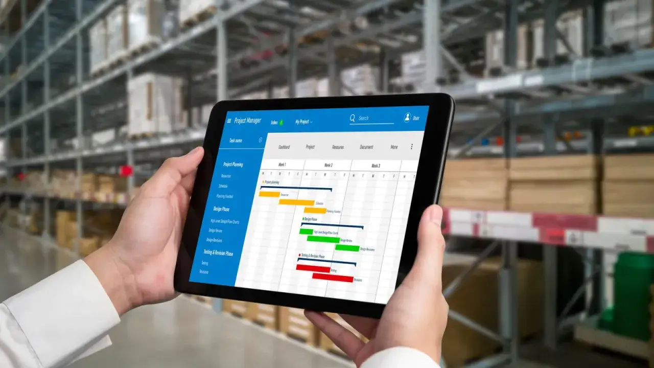 Menedżer projektu sprawdza harmonogram na tablecie, aby wszystko było na czas w magazynie.