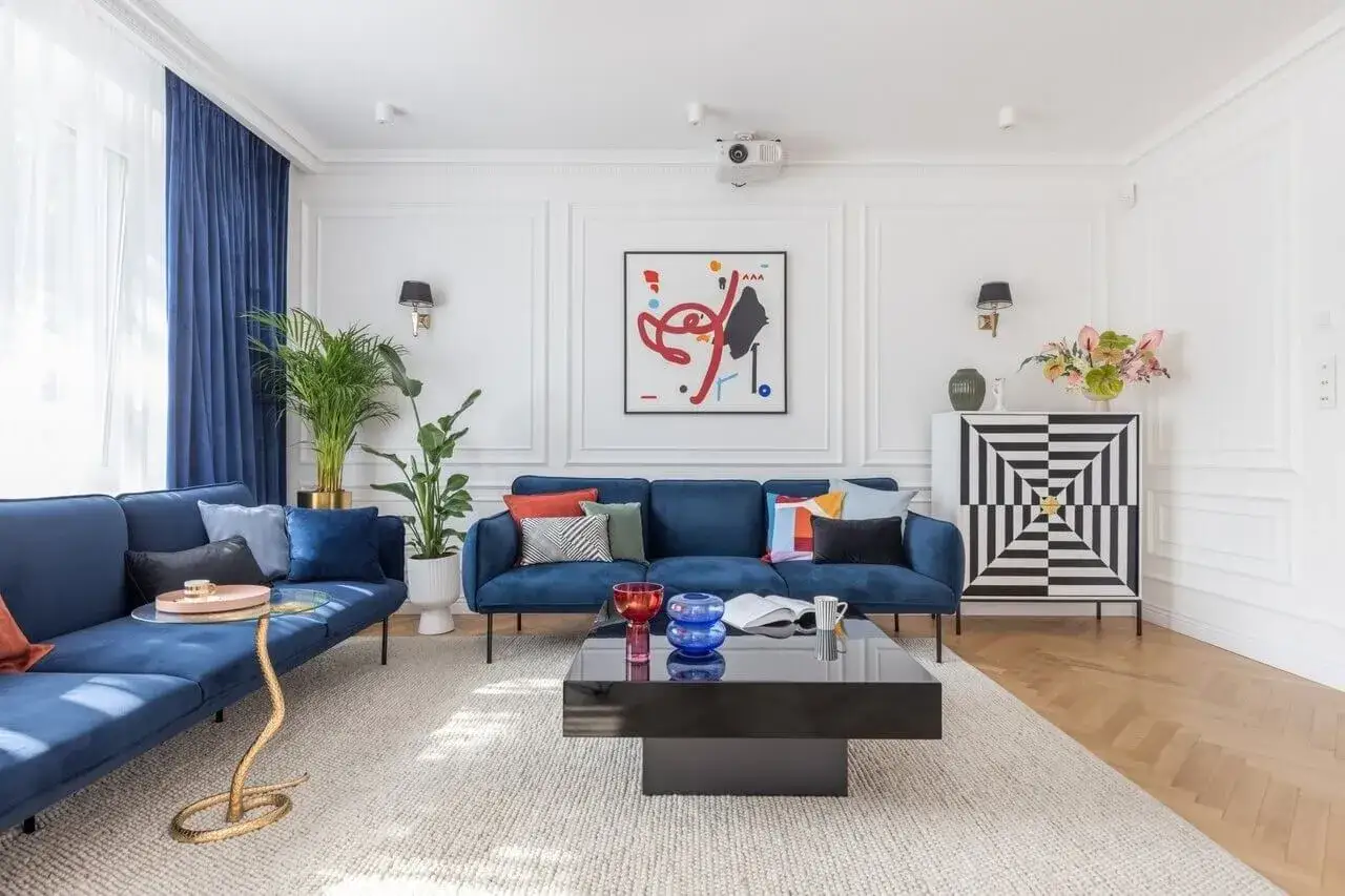 Elegancki salon w stylu paryskim z granatowymi sofami, geometryczną komodą i abstrakcyjnym obrazem.
