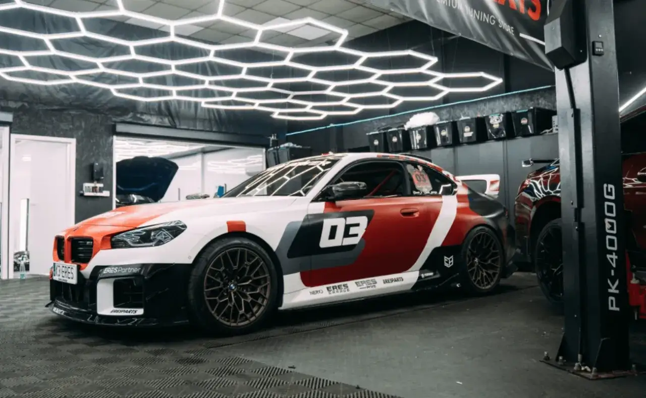 Wyścigowe BMW w garażu, gotowe do tuningu. Biało-czerwona karoseria z numerem 
