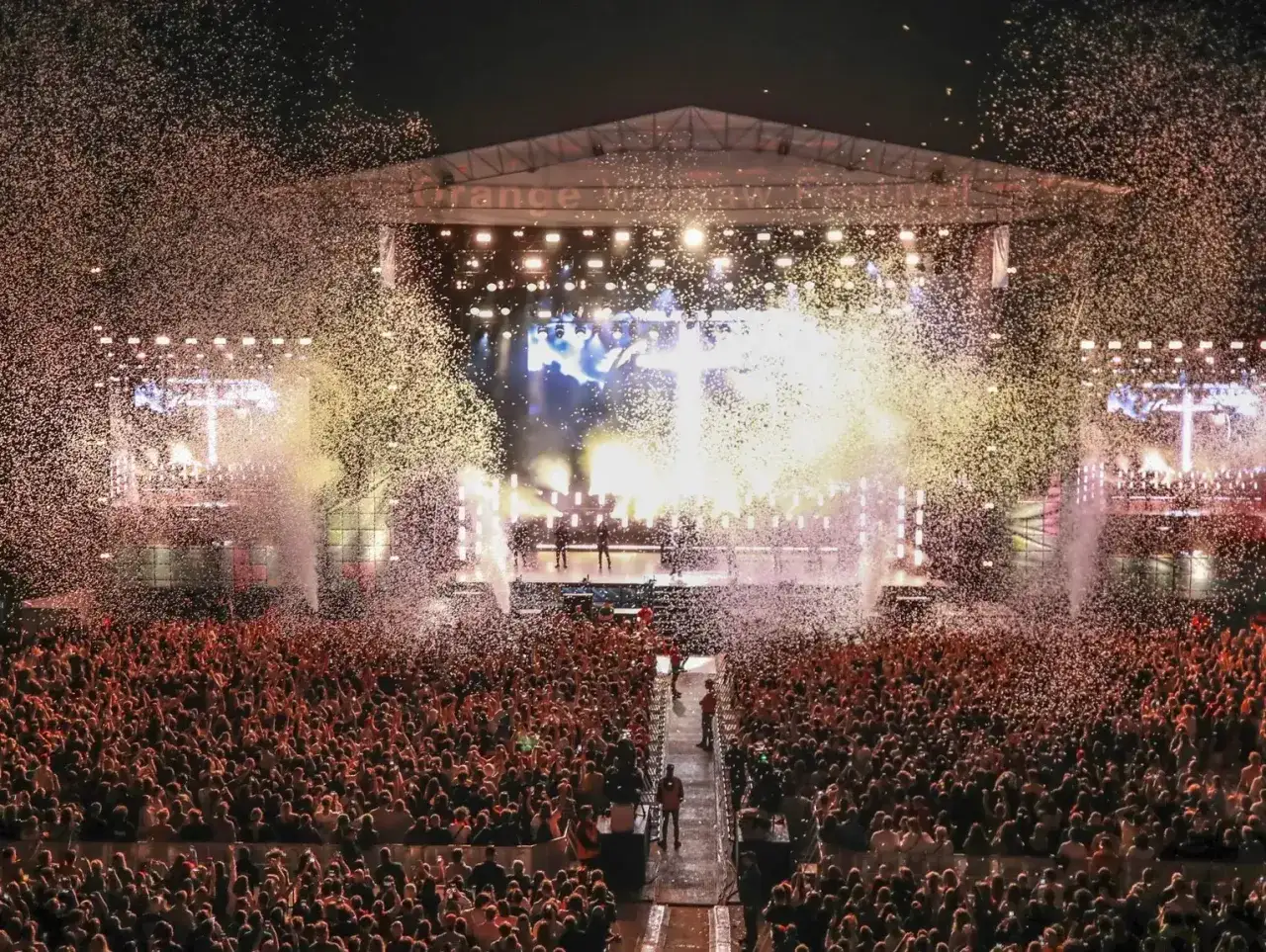 Tłum szaleje na koncercie, konfetti sypie się z góry. Wielka scena, światła i muzyka tworzą atmosferę festiwalu Orange Warsaw.
