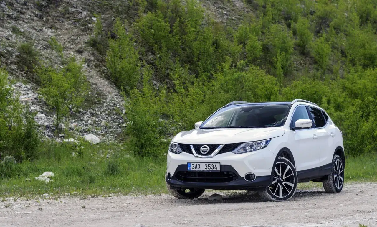 Biały Nissan Qashqai na drodze szutrowej, otoczony zielenią. Zastanawiasz się, ile wytrzyma silnik Nissan Qashqai?