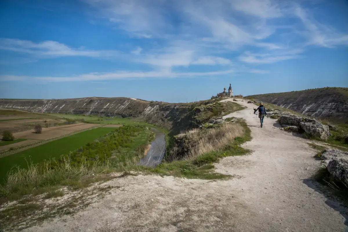 Malownicza trasa w Mołdawii, gdzie ceny wycieczek są przystępne. Widok na kanion z rzeką, pola uprawne i cerkiew na wzgórzu.