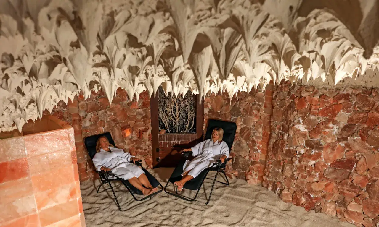 Dwie kobiety w szatach relaksują się w grocie solnej. Warto wiedzieć, jak się ubrać do groty solnej, by czuć się komfortowo.
