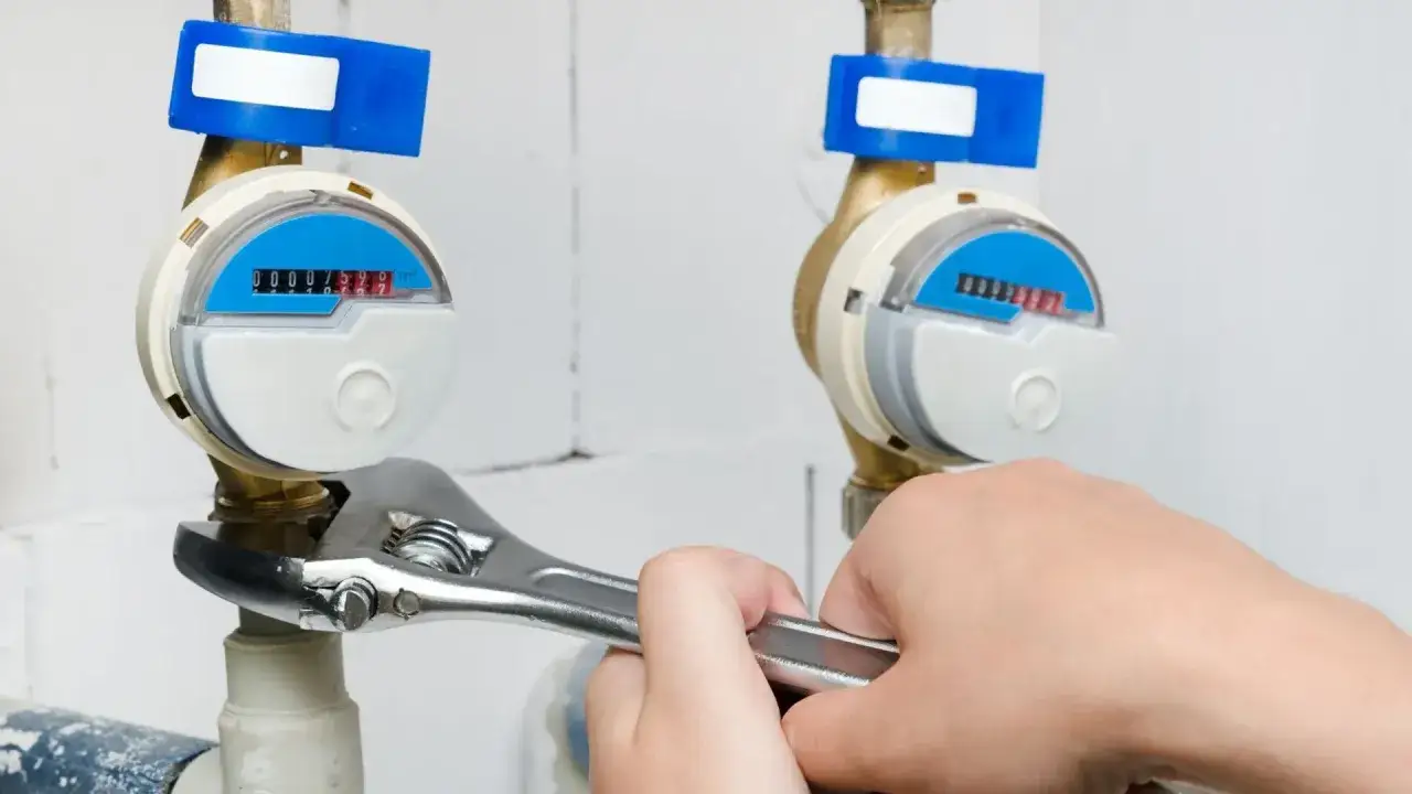 Ręka dokręca kluczem wodomierz. Brak legalizacji wodomierza konsekwencje mogą być dotkliwe.