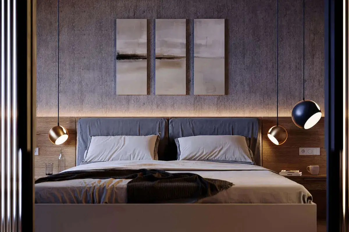 Nowoczesna sypialnia z łóżkiem, obrazami na ścianie i wiszącymi lampami. Jedna z nich to lampa led ścienna w złotym kolorze.