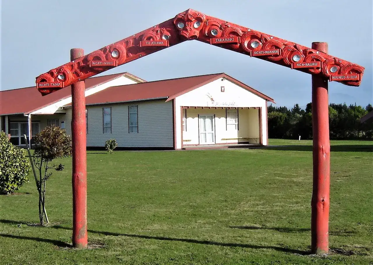 Czerwony, rzeźbiony łuk z nazwami plemion, jakby witał przybyłych, gdy odkryto Nową Zelandię.