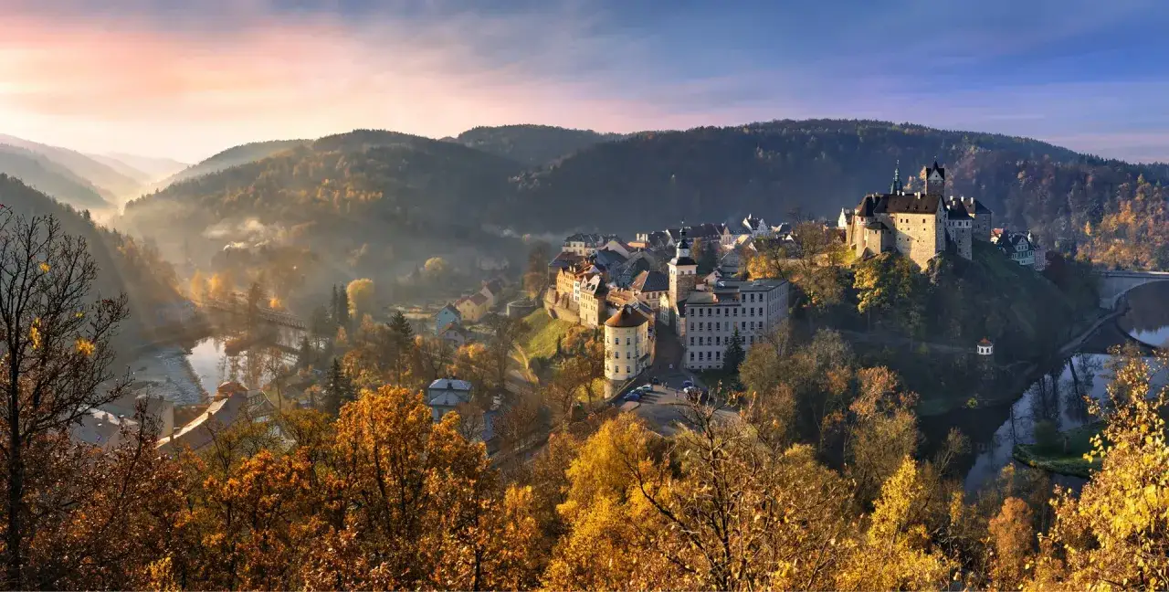 Zamek Loket góruje nad jesienną doliną rzeki. Mgła i złote liście tworzą magiczną atmosferę.