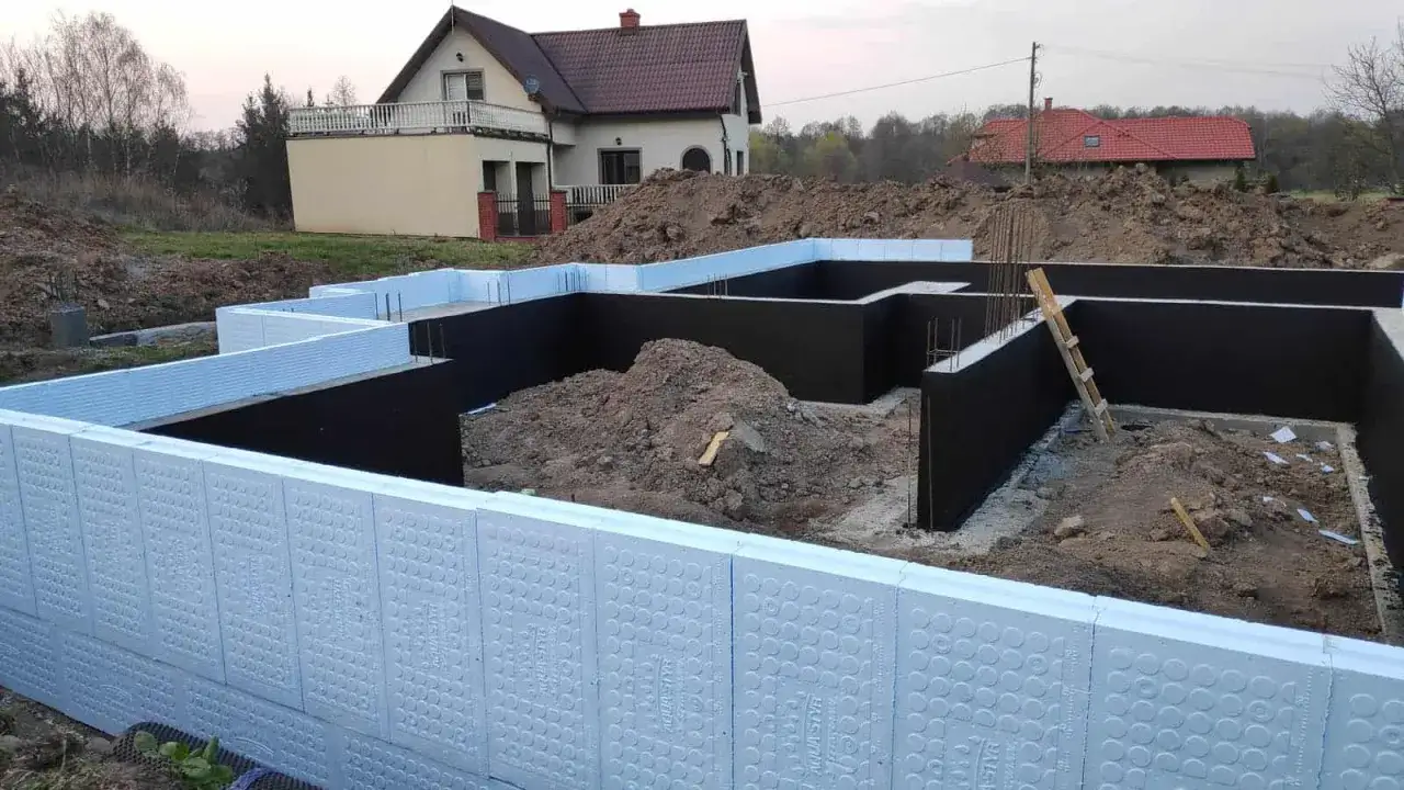 Budowa domu: jak ocieplić fundament styropianem. Widoczne elementy izolacji fundamentów z białego styropianu.