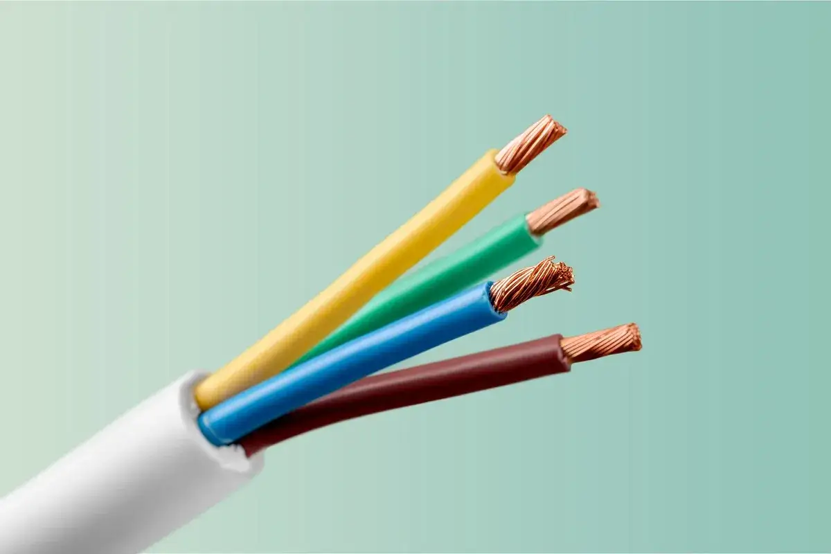 Cztery kolorowe przewody elektryczne: ż&oacute;łty, zielony, niebieski i brązowy, wystające z białej izolacji.