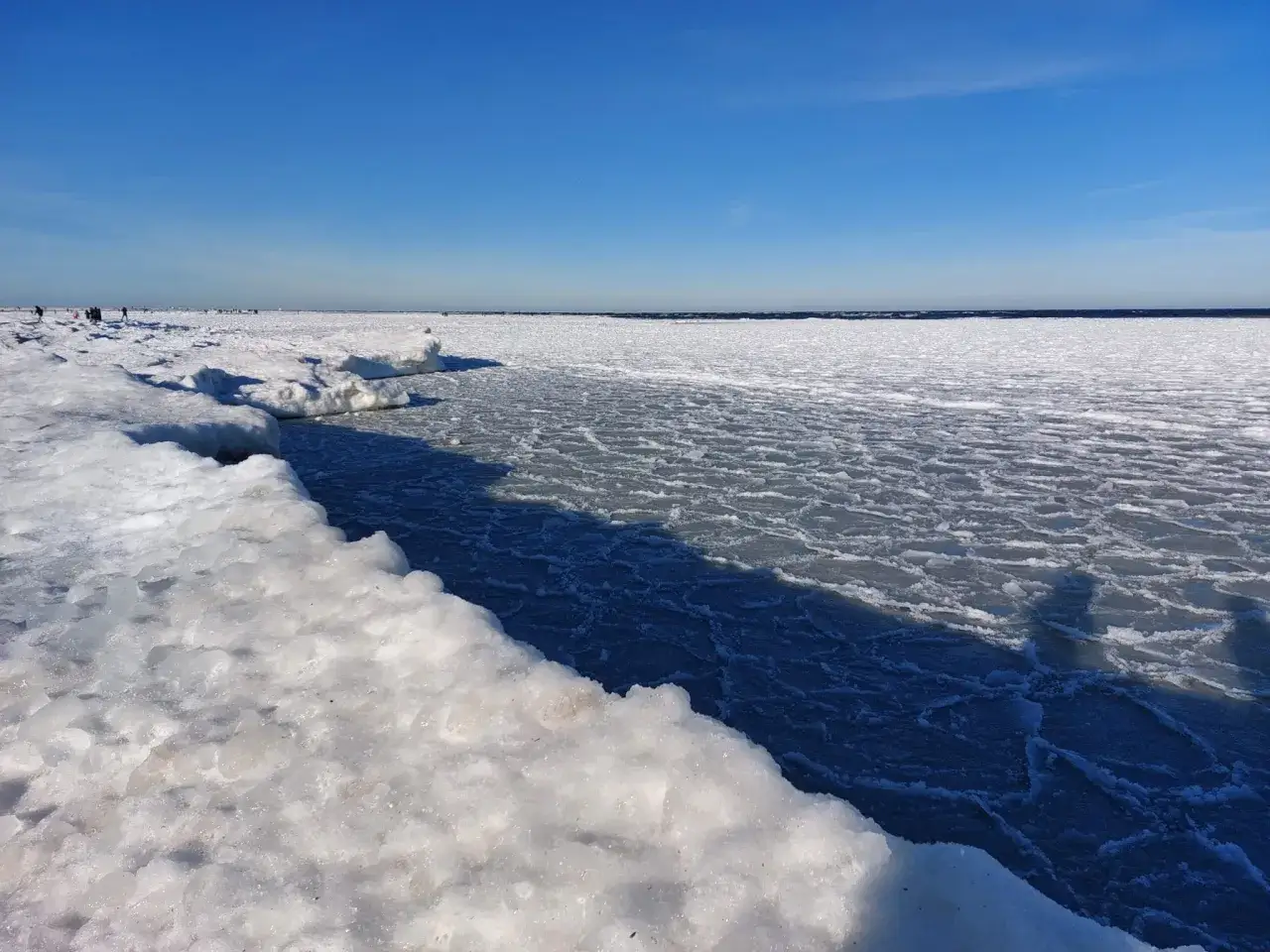 Lodowe krajobrazy Bałtyku, kiedy ostatnio zamarzło morze bałtyckie. Ludzie spacerują po zamarzniętej tafli.
