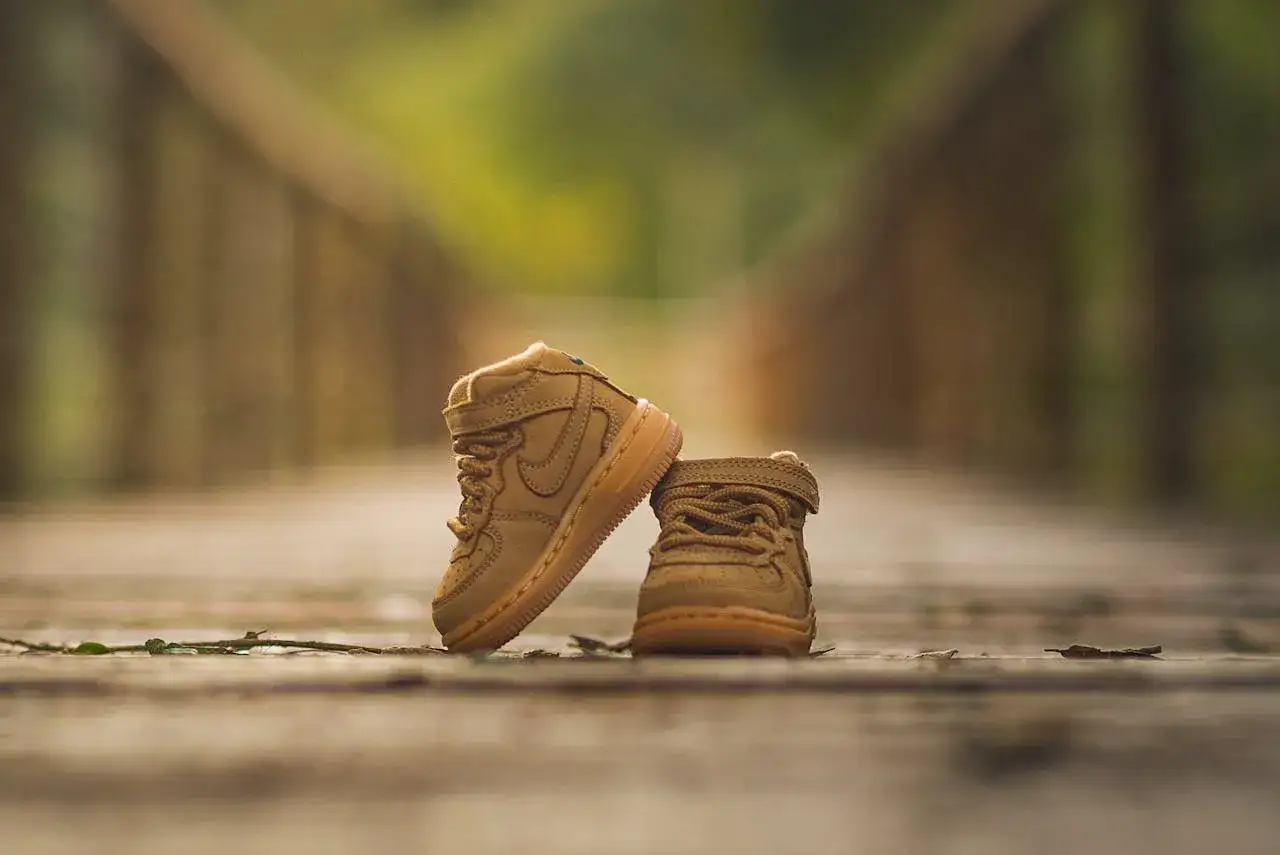 Idealne buty dla dziecka z wysokim podbiciem? Te beżowe, wysokie sneakersy wyglądają na wygodne i stylowe na drewnianym molo.