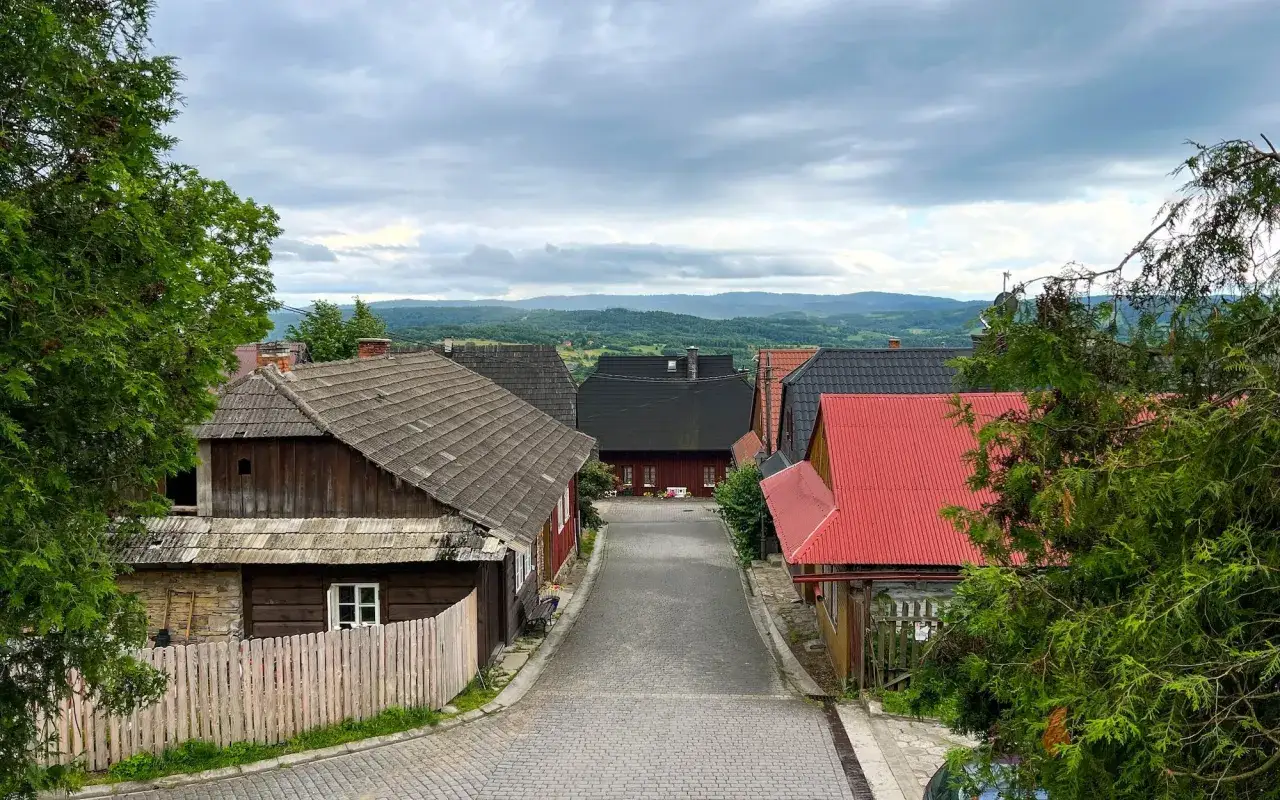 Urokliwa uliczka w Lanckoronie z tradycyjną zabudową i widokiem na Beskidy. Odkryj lanckorońskie atrakcje!