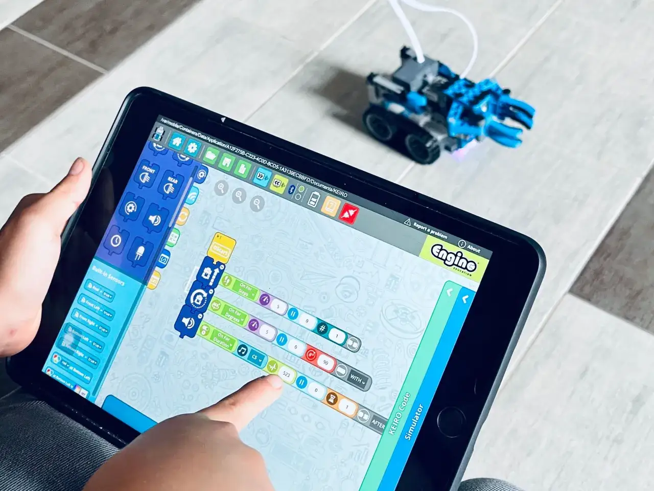 Dziecko programuje robota za pomocą aplikacji na tablecie. To nauka kodowania klasa 3, gdzie tworzy się własne algorytmy.