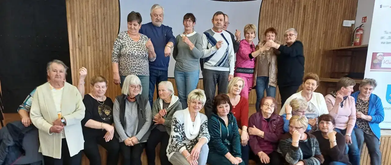 Grupa seniorów, którzy uczą się, jak założyć klub seniora. Wszyscy uśmiechnięci i gotowi do działania.
