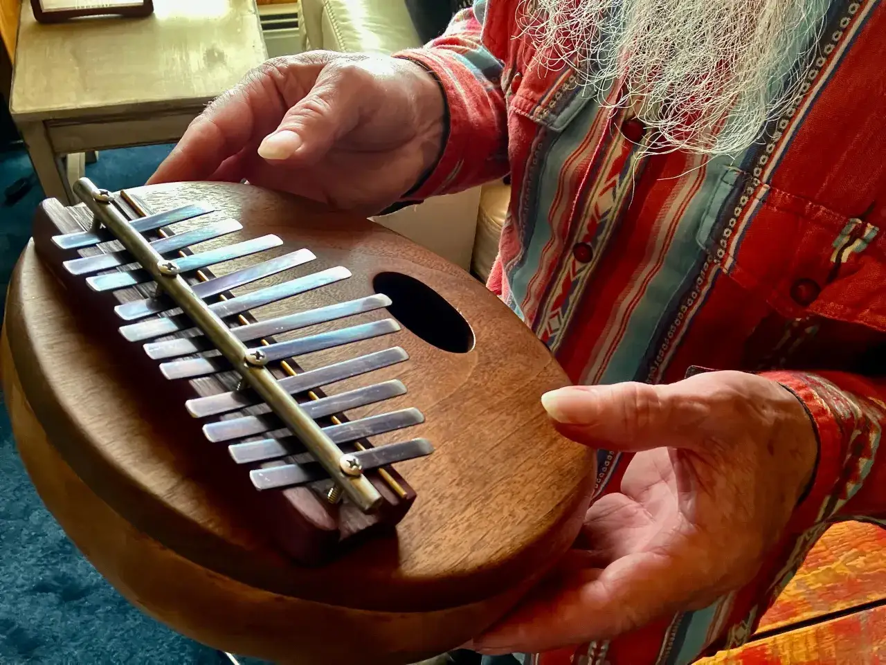 Dłonie trzymają kalimbę, pokazując, jak grać na tym instrumencie.