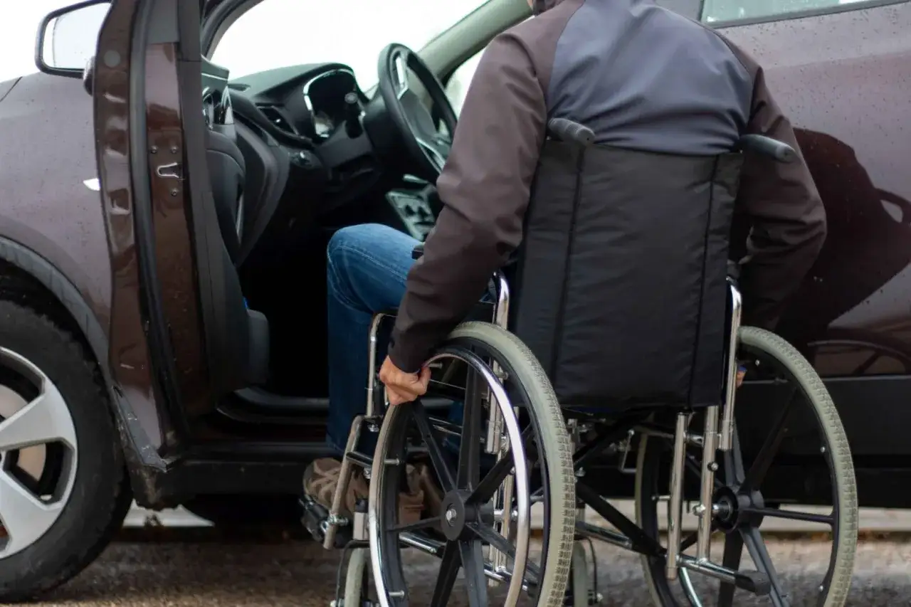 Osoba na wózku inwalidzkim wsiada do samochodu. Ulga rehabilitacyjna 400 zł może pomóc w takich sytuacjach.