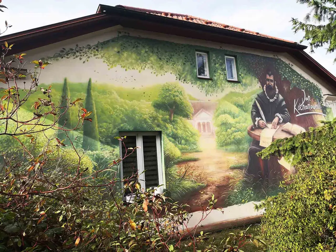 Mural przedstawia Jana Kochanowskiego, który siedzi przy stole i pisze. Obraz nawiązuje do jego życia i twórczości, ukazując go w otoczeniu natury.
