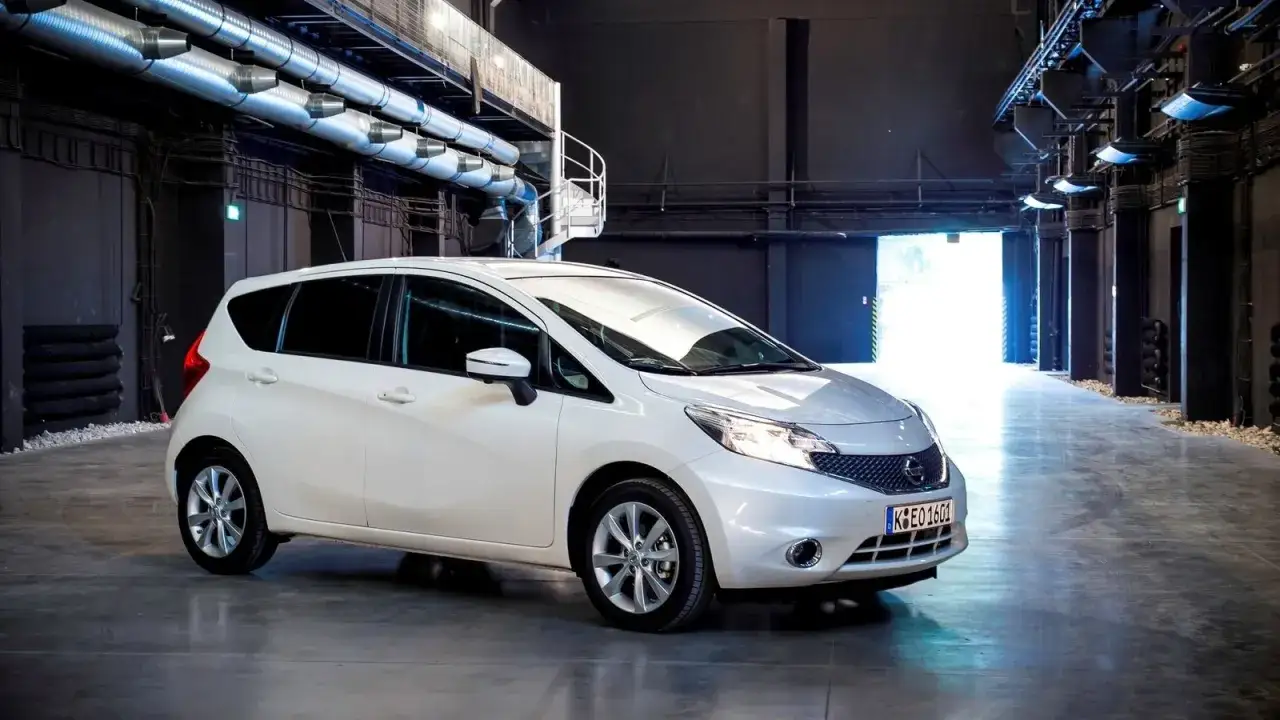 Biały Nissan Note stoi w industrialnym wnętrzu.