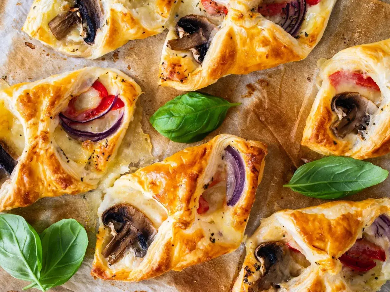 Chrupiące ciasto francuskie z pieczarkami, serem, czerwoną cebulą i papryką. Idealne na szybką przekąskę.