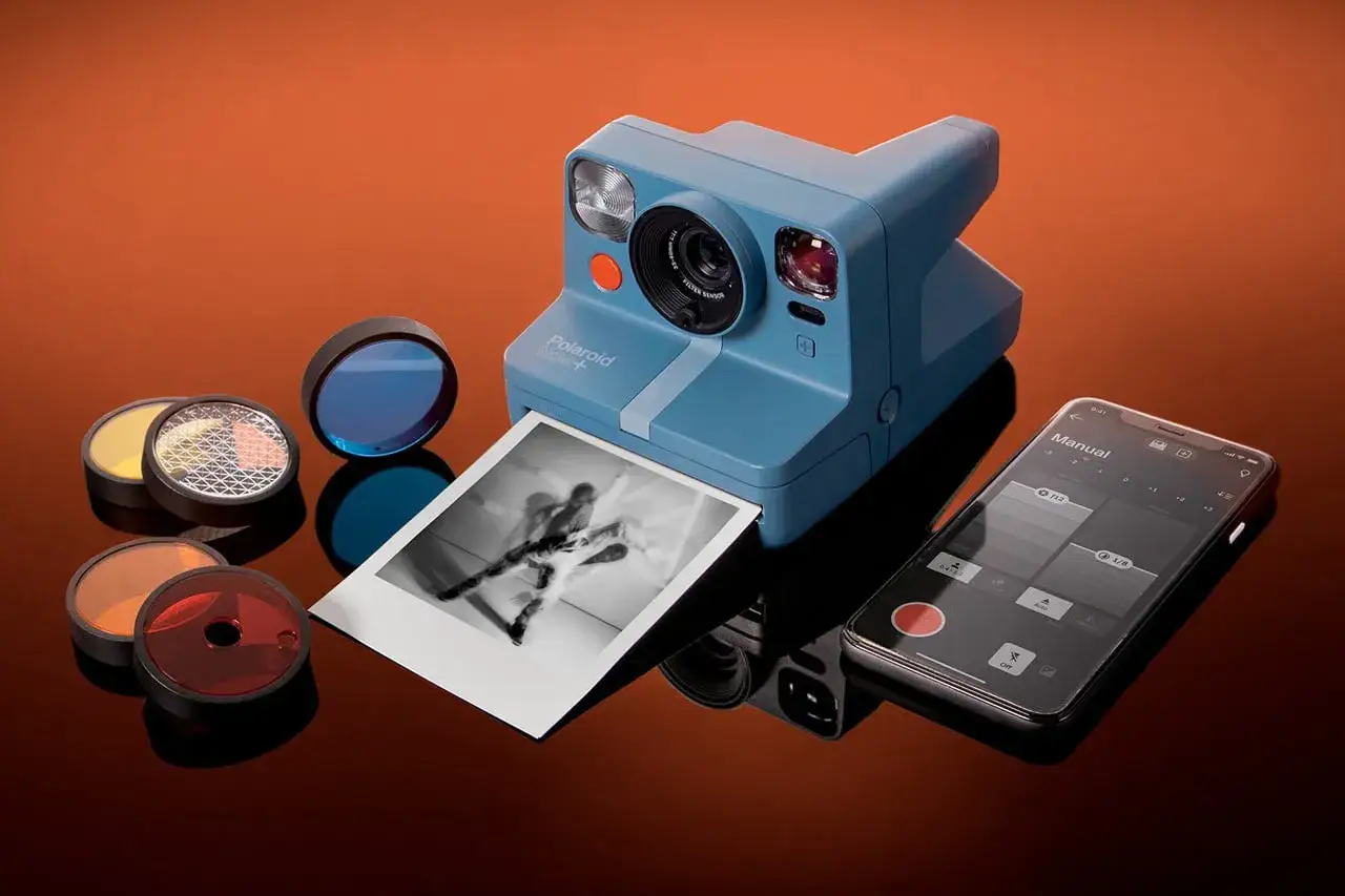 Niebieski aparat fotograficzny który drukuje zdjęcia, z filtrami i smartfonem.